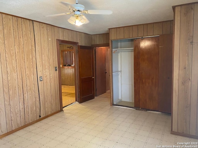 unfurnished bedroom featuring ceiling fan and wooden walls