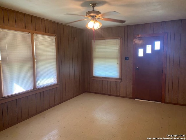 foyer entrance featuring ceiling fan and wooden walls