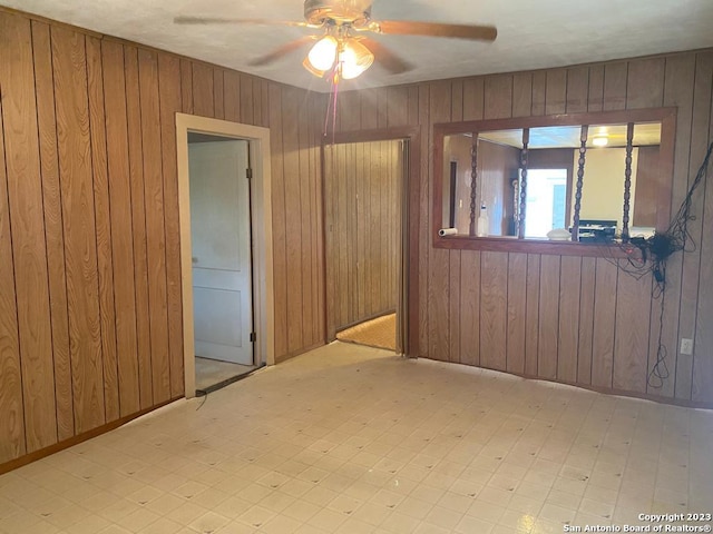 empty room featuring wooden walls and ceiling fan