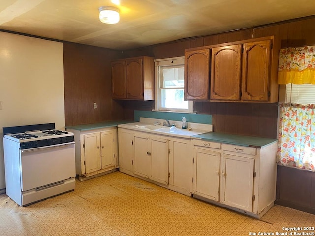 17770 Interstate 35, Lytle, TX 78052 - kitchen with white gas range, light floors, light countertops, wood walls, and a sink