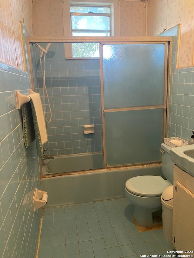 17770 Interstate 35, Lytle, TX 78052 - bathroom featuring tile walls, tile patterned flooring, toilet, vanity, and enclosed tub / shower combo