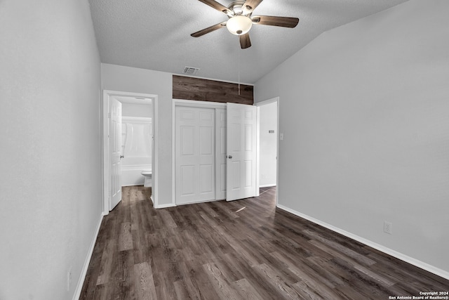 unfurnished bedroom featuring ceiling fan, dark wood-type flooring, ensuite bathroom, a textured ceiling, and lofted ceiling