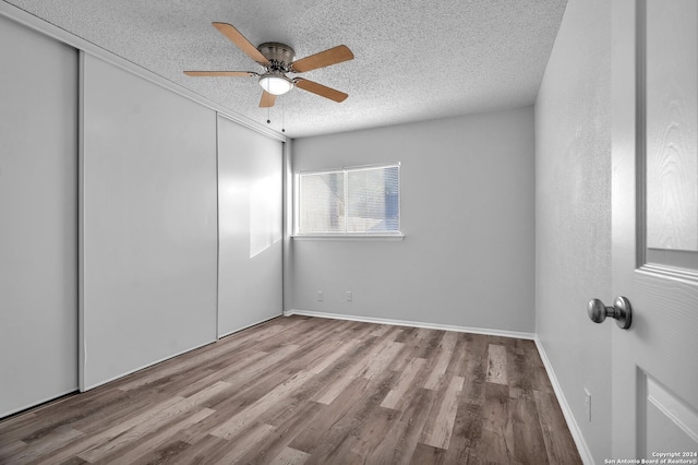 unfurnished bedroom featuring a textured ceiling, light wood-type flooring, a closet, and ceiling fan