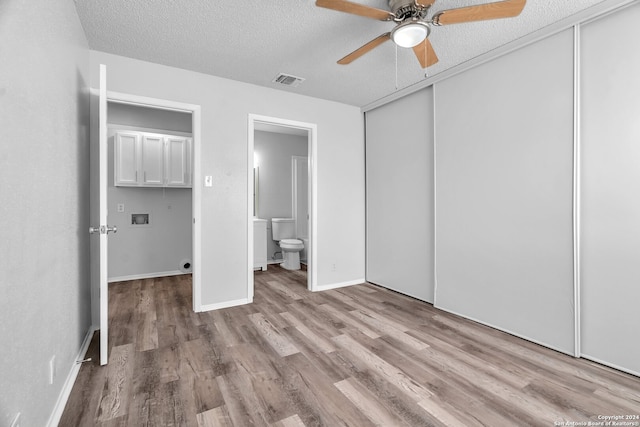 unfurnished bedroom featuring a textured ceiling, ceiling fan, connected bathroom, light hardwood / wood-style floors, and a closet