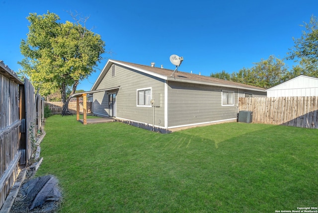 back of house with a lawn and central AC