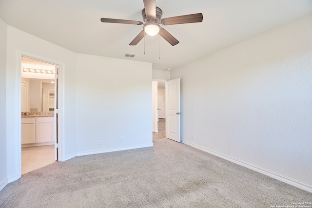 unfurnished bedroom with ceiling fan, ensuite bathroom, and light carpet