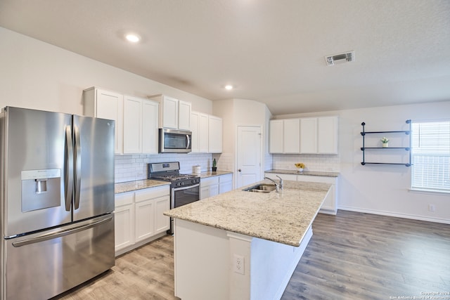 kitchen with appliances with stainless steel finishes, sink, a center island with sink, hardwood / wood-style floors, and white cabinetry