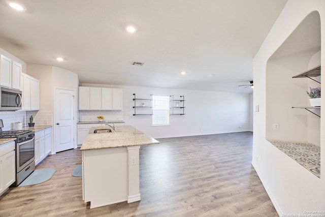 kitchen featuring a center island with sink, white cabinets, sink, light hardwood / wood-style flooring, and appliances with stainless steel finishes