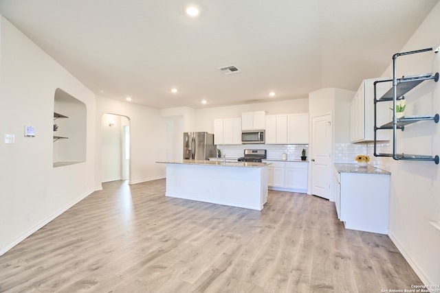 kitchen featuring light stone countertops, white cabinetry, an island with sink, and appliances with stainless steel finishes