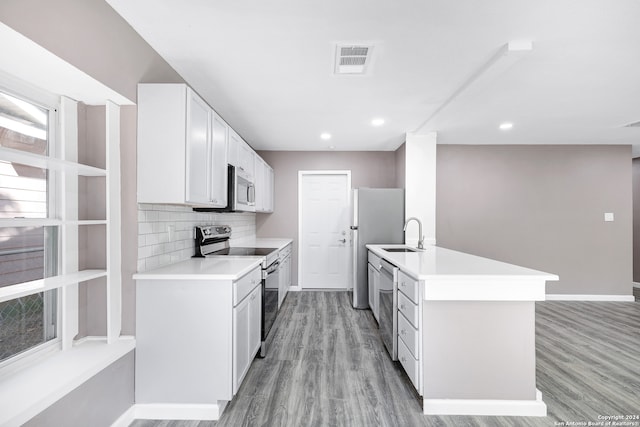 kitchen featuring sink, light hardwood / wood-style floors, decorative backsplash, white cabinets, and appliances with stainless steel finishes