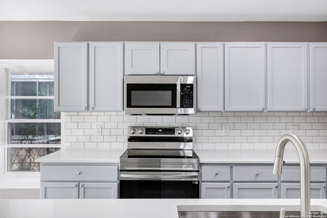 kitchen with decorative backsplash, sink, white cabinets, and stainless steel appliances