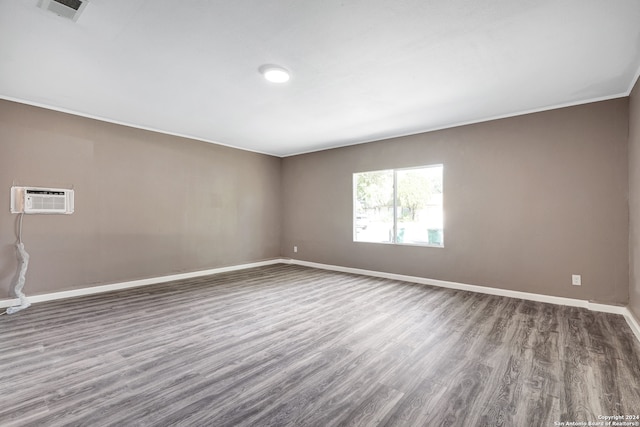 unfurnished room featuring hardwood / wood-style floors and a wall mounted air conditioner