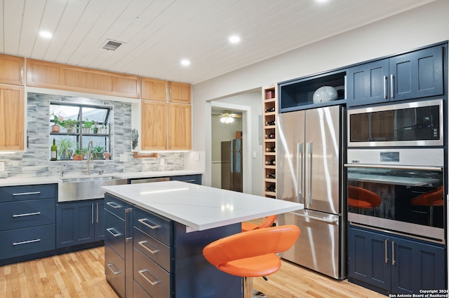 kitchen featuring blue cabinetry, backsplash, stainless steel appliances, and a kitchen island