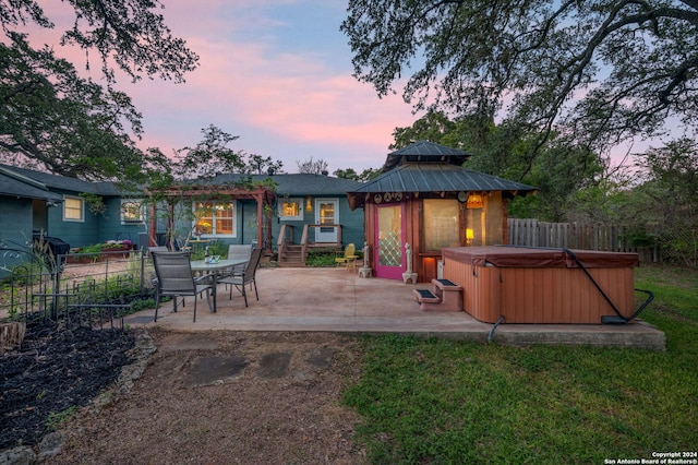 back house at dusk with a gazebo, a yard, a patio, and a hot tub