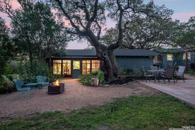 back house at dusk featuring a patio area and an outdoor fire pit