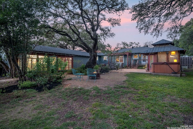 yard at dusk featuring a patio area and a hot tub