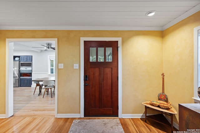 foyer featuring light wood-type flooring, ceiling fan, and crown molding