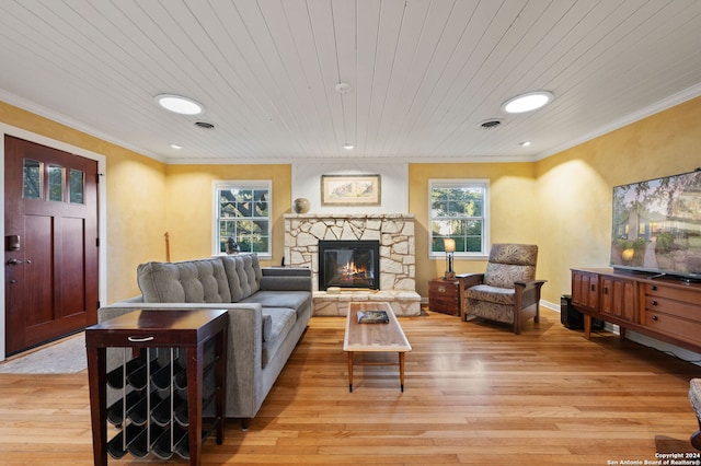 living room featuring a stone fireplace, a wealth of natural light, light hardwood / wood-style flooring, and wood ceiling