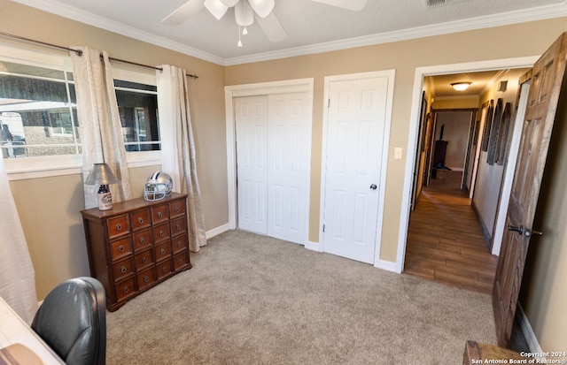 bedroom featuring a textured ceiling, ceiling fan, crown molding, and light carpet