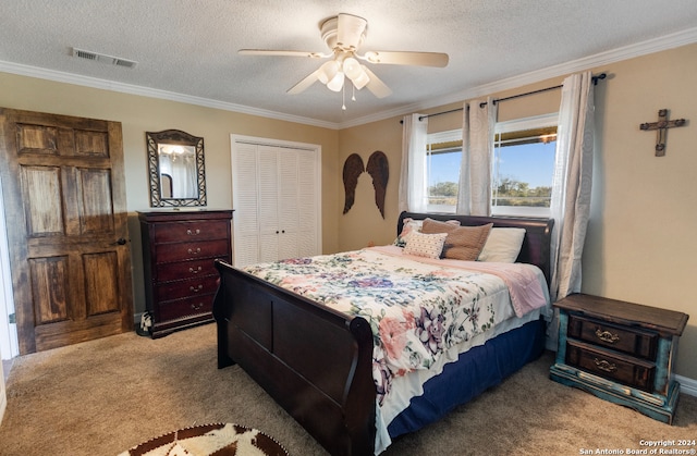 carpeted bedroom with ceiling fan, ornamental molding, a textured ceiling, and a closet