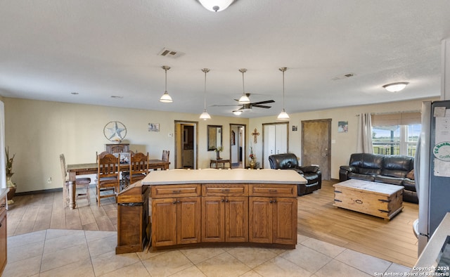 kitchen featuring pendant lighting, light wood-type flooring, a kitchen island, and ceiling fan