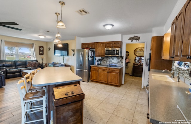 kitchen with sink, a center island, tasteful backsplash, pendant lighting, and appliances with stainless steel finishes