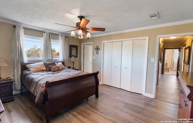 bedroom featuring wood-type flooring, a textured ceiling, ceiling fan, and crown molding