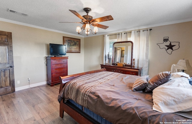 bedroom with ceiling fan, hardwood / wood-style floors, crown molding, and a textured ceiling