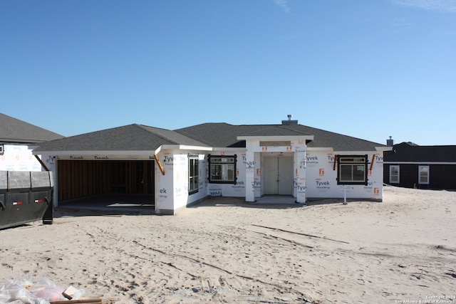 unfinished property with an attached garage and a shingled roof