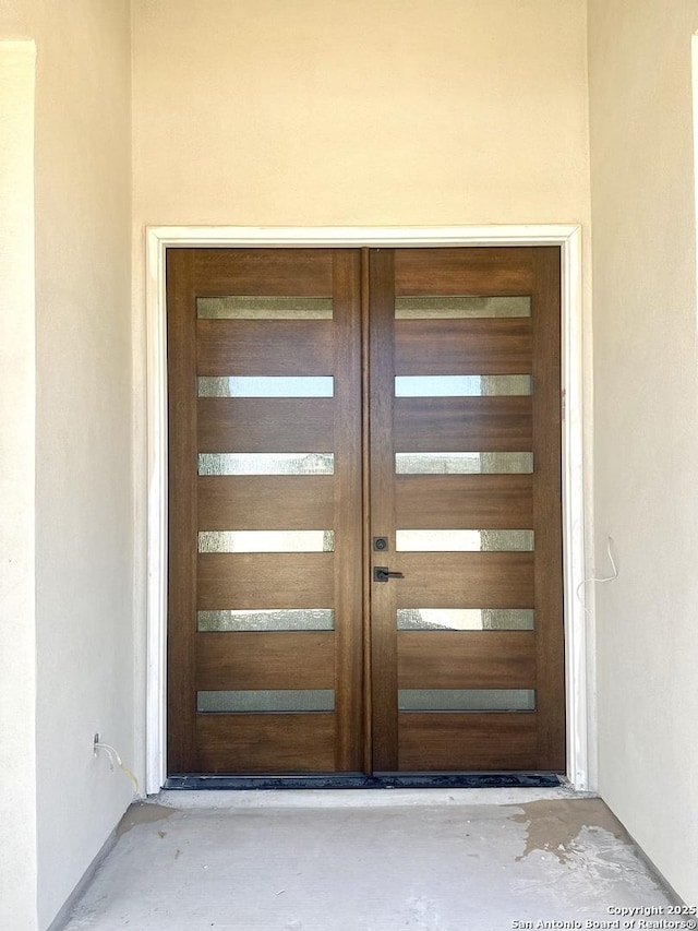 view of exterior entry with a garage and stucco siding