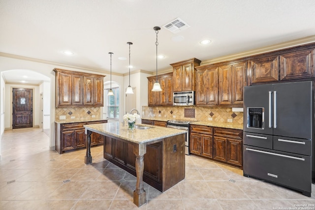 kitchen with appliances with stainless steel finishes, a breakfast bar, sink, a center island with sink, and decorative light fixtures