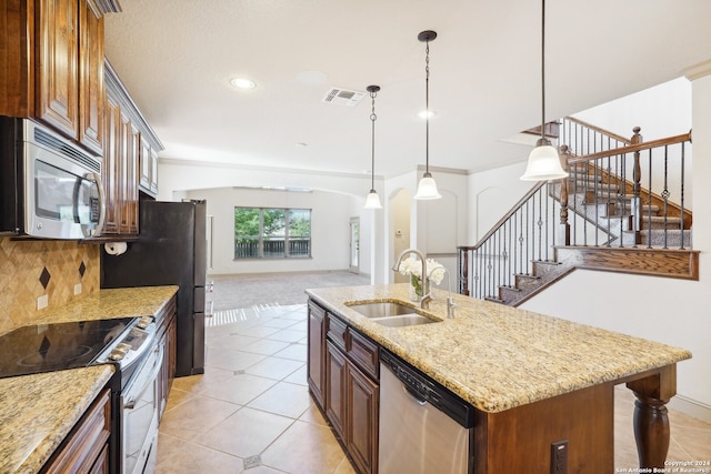 kitchen with sink, stainless steel appliances, backsplash, decorative light fixtures, and a kitchen island with sink