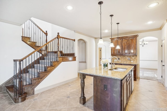 kitchen featuring crown molding, sink, hanging light fixtures, decorative backsplash, and light stone countertops