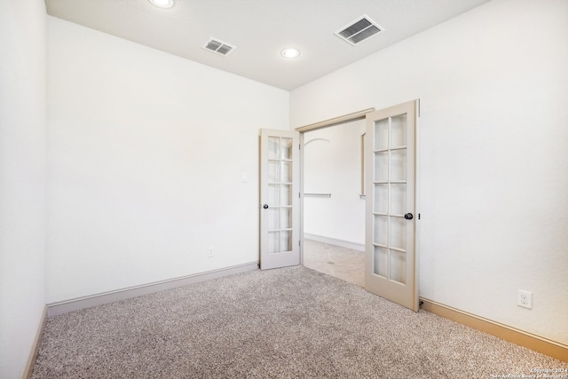 spare room featuring light carpet and french doors