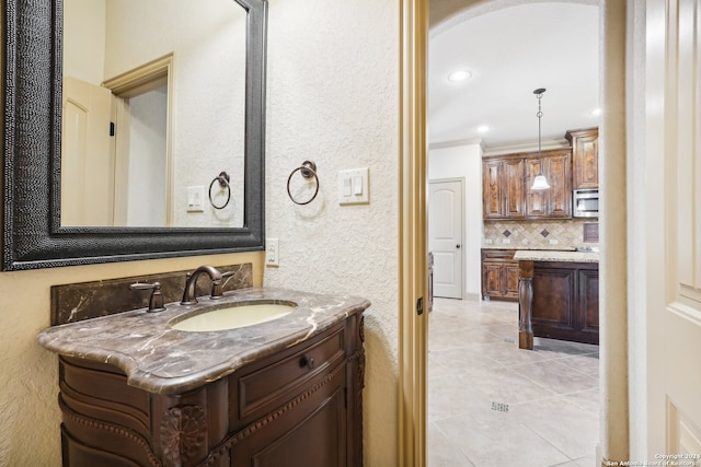 bathroom with tile patterned floors, vanity, ornamental molding, and backsplash