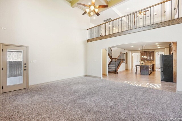 102 Santa Anita, Boerne, TX 78006 - unfurnished living room featuring arched walkways, a towering ceiling, light carpet, stairway, and beamed ceiling