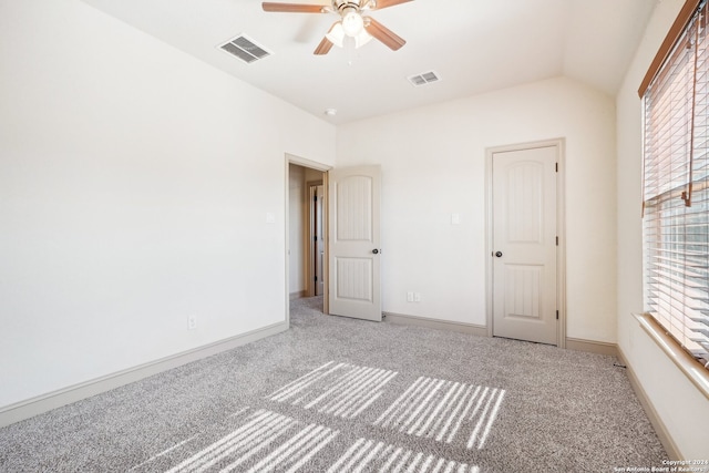 unfurnished bedroom with ceiling fan, lofted ceiling, carpet floors, and multiple windows