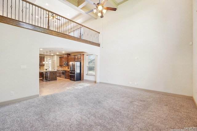 102 Santa Anita, Boerne, TX 78006 - unfurnished living room featuring light colored carpet, arched walkways, a ceiling fan, beam ceiling, and baseboards