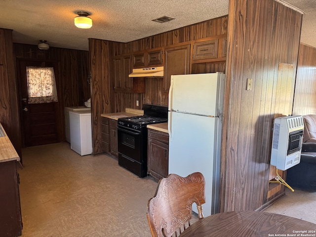 kitchen with black range with gas stovetop, heating unit, wooden walls, white refrigerator, and washer / clothes dryer