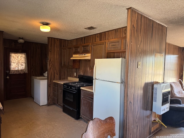 kitchen with heating unit, wooden walls, black gas stove, white fridge, and washer / dryer