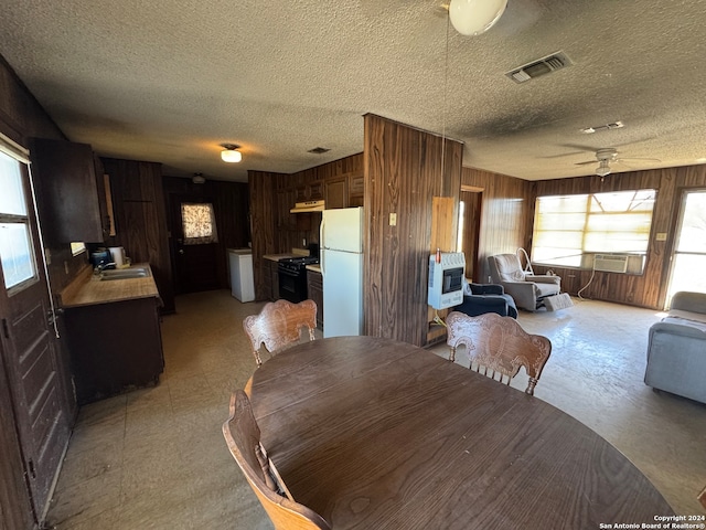 dining room with ceiling fan, wood walls, sink, and a textured ceiling