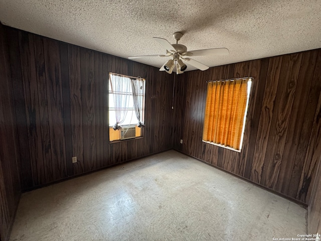 unfurnished room featuring a textured ceiling, ceiling fan, cooling unit, and wood walls