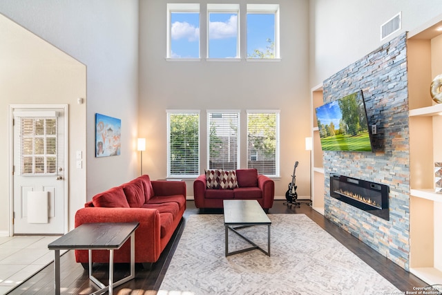 living room with a stone fireplace, a towering ceiling, and dark hardwood / wood-style floors