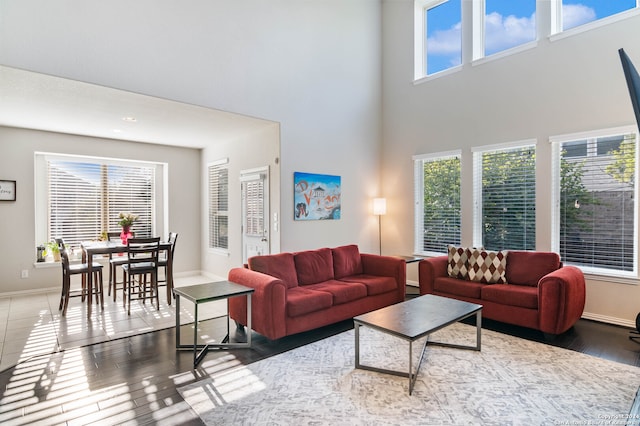 living room featuring a wealth of natural light, dark hardwood / wood-style flooring, and a high ceiling