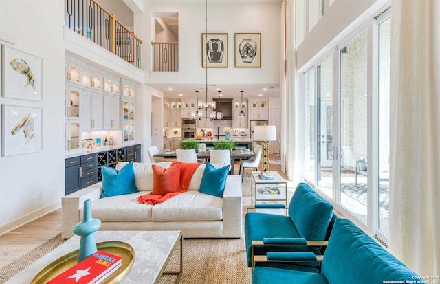 living room featuring a chandelier, a towering ceiling, and light hardwood / wood-style floors