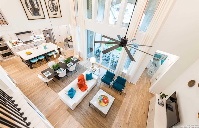 living room featuring a high ceiling, ceiling fan, and wood-type flooring