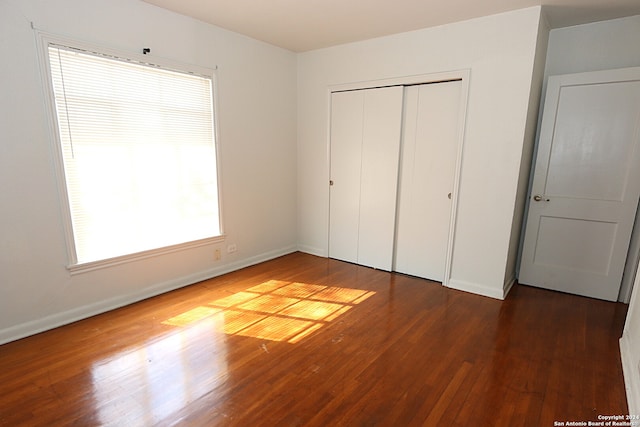 unfurnished bedroom featuring a closet and dark wood-type flooring