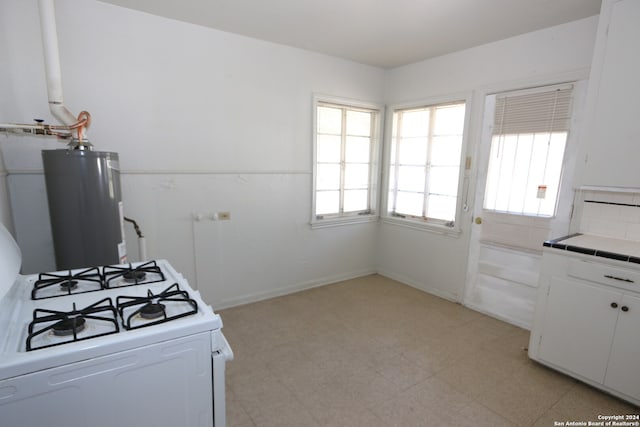 kitchen featuring white cabinets, plenty of natural light, white range with gas stovetop, and water heater