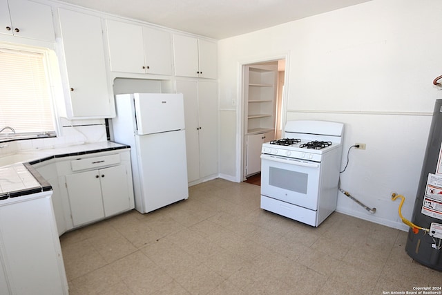 kitchen with white cabinetry, tile counters, water heater, and white appliances