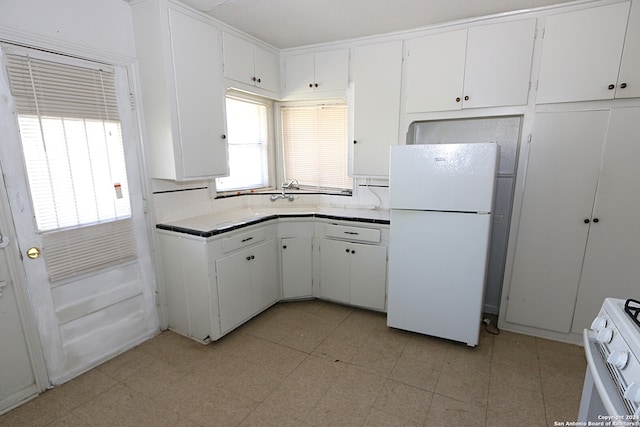 kitchen with decorative backsplash, white cabinets, and white appliances